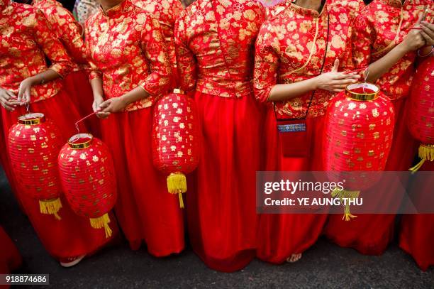 Young women in traditional Chinese costumes hold lanterns as they take part in celebrations marking the first day of the Lunar New Year in Yangon's...