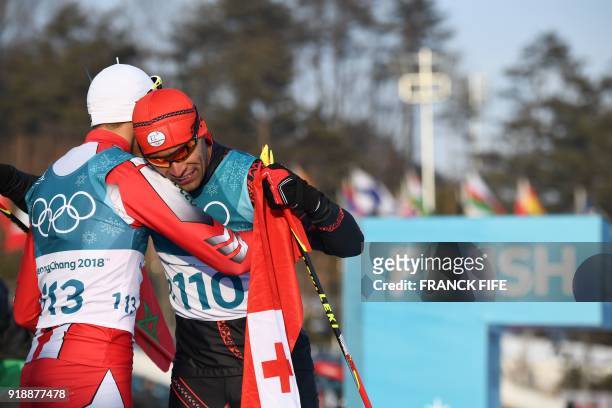 Morocco's Samir Azzimani congratulates Tonga's Pita Taufatofua after he crossed the finish line during the men's 15km cross country freestyle at the...