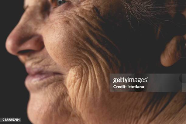 wrinkled face of elderly woman, smiling details - wrinkles fotografías e imágenes de stock