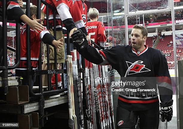 Young Hurricanes fan high-fives Aaron Ward of the Carolina Hurricanes after the pre-game skate before a NHL game against the Pittsburgh Penguins on...