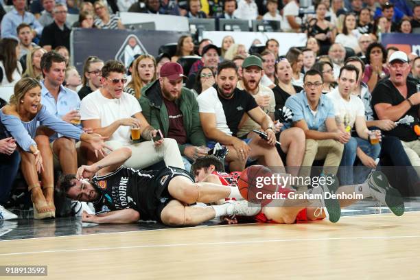 Peter Hooley of Melbourne United and Damian Martin of the Wildcats crash into the crowd during the round 19 NBL match between Melbourne United and...