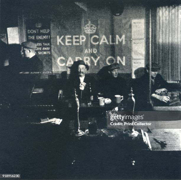 'Carry On', 1941. Men sit in a local pub and follow the government's advice to 'Keep Calm and Carry On'. From Air of Glory, by Cecil Beaton. [His...