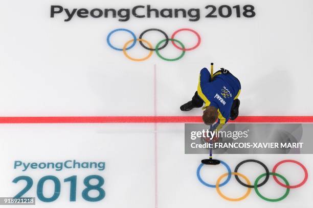 Sweden's Rasmus Wrana brushes the ice in front of the stone during the curling men's round robin session between Sweden and Britain during the...