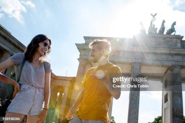 young couple laughing in front of brandenburg gate brandenburger tor with lens flare - berlin fotografías e imágenes de stock