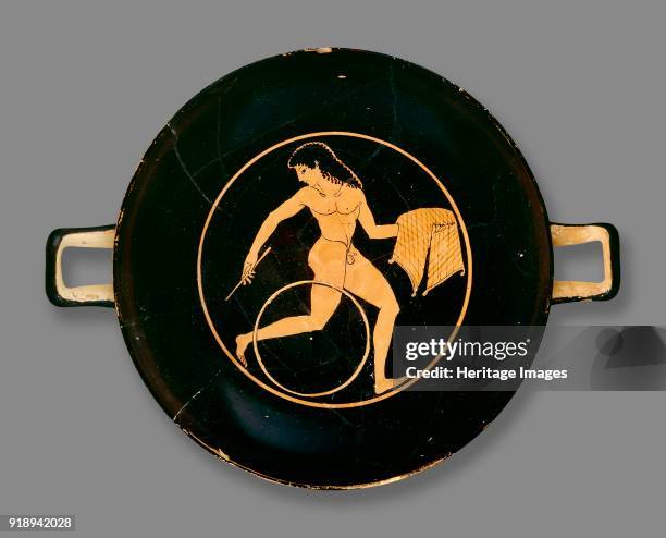 Attic red-figure cup showing a boy running with a hoop and a tray of food in the inside, 6th-5th century BC. Athenian red-figure cup; boy with a hoop...