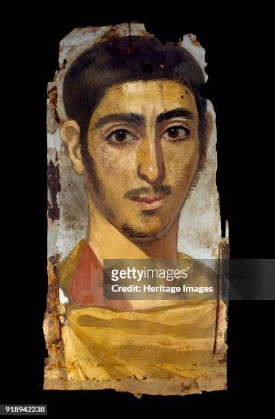 Mummy portrait in encaustic on wood panel: young man, perhaps a soldier, wearing a cloak fastened with a gold brooch, 193 - 235. Cloak fastened at...