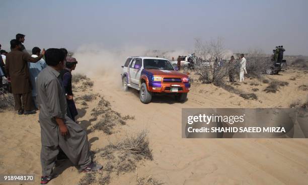 Pakistani driver past spectators during the Cholistan Desert Jeep Rally in Derawar on February 16, 2018. - More than 100 drivers have registered for...