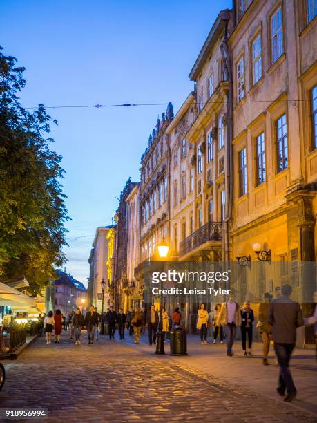 Tourists at sunset on Rynok or Market Square, the main square in the old town of Lviv, in Ukraine. Its well preserved architecture, which blends...