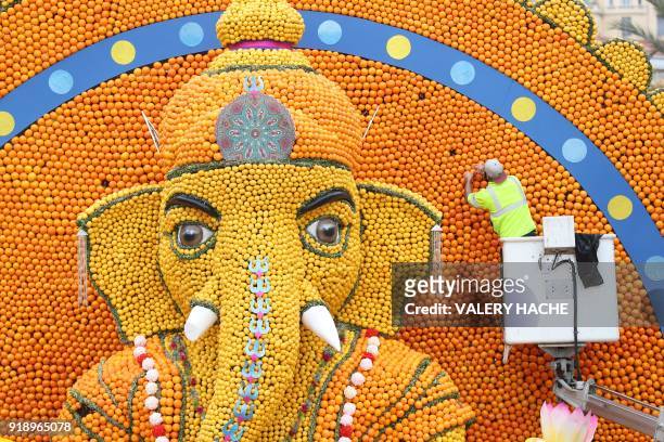 Worker places oranges on a sculpture of Hindu deity Ganesh, made of lemons and oranges, on the eve of the 85th Lemon Festival, on February 16, 2018...