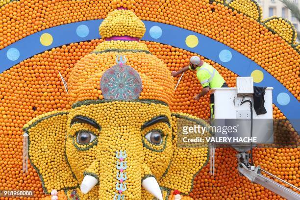 Worker on a mobile elevating platform checks a sculpture of Hindu deity Ganesh, made of lemons and oranges, on the eve of the 85th Lemon Festival, on...