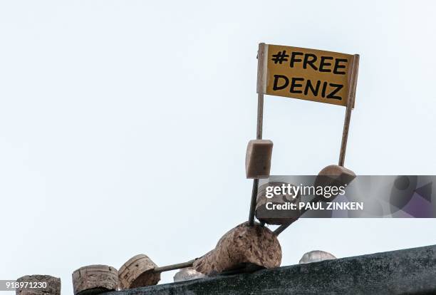 "#FreeDeniz" is written on the sign of a so-called street yogi figure made of cork sitting on a street sign in Berlin on February 16 pictured after...