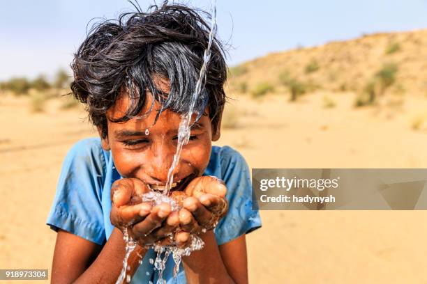 indiase jongen drinken vers water, woestijn dorp, rajasthan, india - putten stockfoto's en -beelden