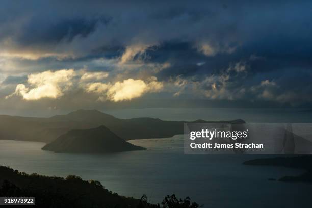 active taal volcano at dawn in the middle of lake taal, itself the result of eruptions over 100,000 years ago, with fish traps in the foreground, tagaytay, luzon island, philippines - tagaytay stock pictures, royalty-free photos & images