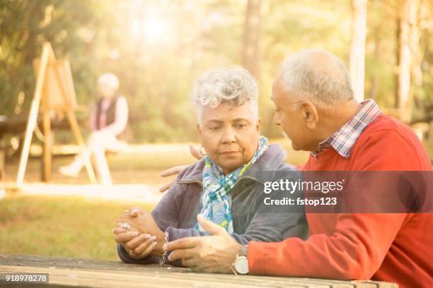 distressed senior adult couple talk at outdoor park. - autumn sadness stock pictures, royalty-free photos & images