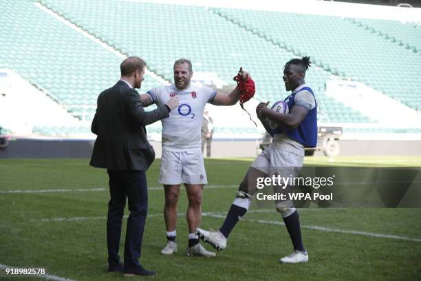 Prince Harry shares a joke with England rugby players James Haskell and Maro Itoje as he attends the England rugby team's open training session as...