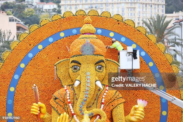 Worker on a mobile elevating platform checks a sculpture of Hindu deity Ganesh, made of lemons and oranges, on the eve of the 85th Lemon Festival, in...