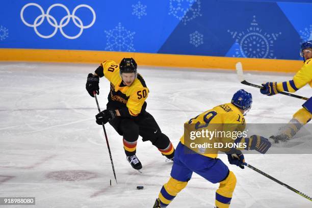 Germany's Patrick Hager controls the puck past Sweden's Erik Gustafsson in the men's preliminary round ice hockey match between Sweden and Germany...