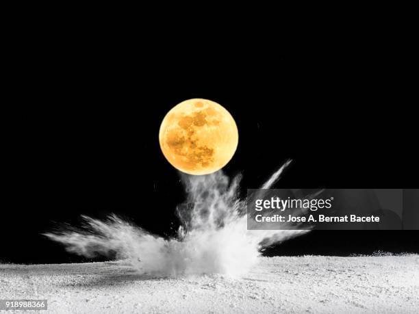 impact of full moon (super moon) on the soil, producing an explosion and a crater of powder on a black background. spain - supermoon stock-fotos und bilder