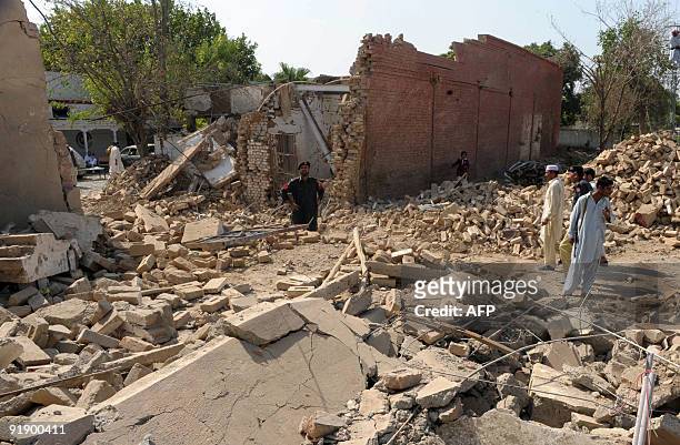 Pakistani policemen stand beside a damaged police station after a suicide car bomb blast in the town of Kohat on October 15, 2009. A suicide bomber...