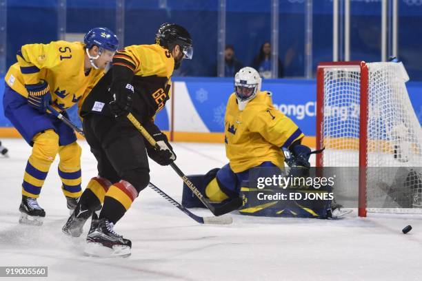 Sweden's Jhonas Enroth guards against a shot from Germany's Felix Schutz in the men's preliminary round ice hockey match between Sweden and Germany...