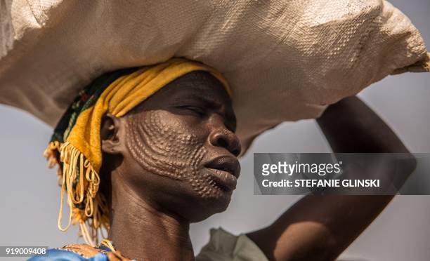 Woman from Nuer ethnic group carries her food after a monthly food distribution at the Protection of Civilian site in Bentiu, South Sudan, on...