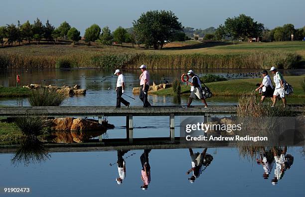 Paul McGinley of Ireland and Richard Finch of England cross the bidge on the 14th hole with their caddies during the first round of the Portugal...