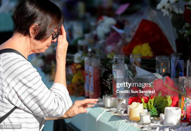 Linda Barrio crosses herself as she prays Friday morning, Feb. 16, 2018 at a memorial at Pine Trails Park in Parkland for the 17 people killed...