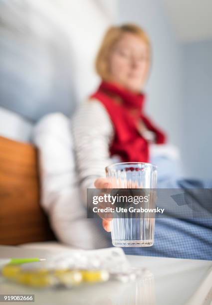 Bonn, Germany Posed Scene: A sick woman is sitting in bed and drinking water on February 13, 2018 in Bonn, Germany.