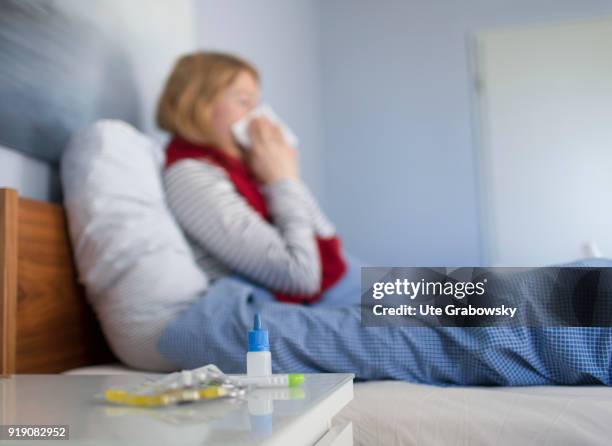 Bonn, Germany Posed Scene: A sick woman sits in bed and cleans her nose on February 13, 2018 in Bonn, Germany.