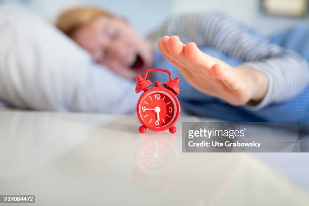 Posed Scene: An alarm clock stands on a bedside table while a woman is sleeping in bed on February 13, 2018 in Bonn, Germany.