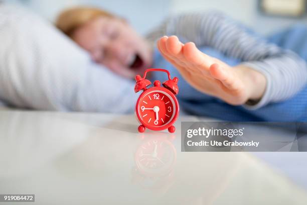 Bonn, Germany Posed Scene: An alarm clock stands on a bedside table while a woman is sleeping in bed on February 13, 2018 in Bonn, Germany.