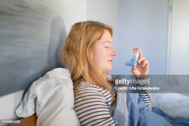 Posed Scene: A sick woman is sitting in bed and using aerosol on February 13, 2018 in Bonn, Germany.