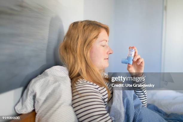 Bonn, Germany Posed Scene: A sick woman is sitting in bed and using aerosol on February 13, 2018 in Bonn, Germany.