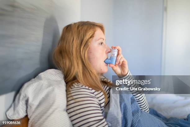 Bonn, Germany Posed Scene: A sick woman is sitting in bed and using aerosol on February 13, 2018 in Bonn, Germany.