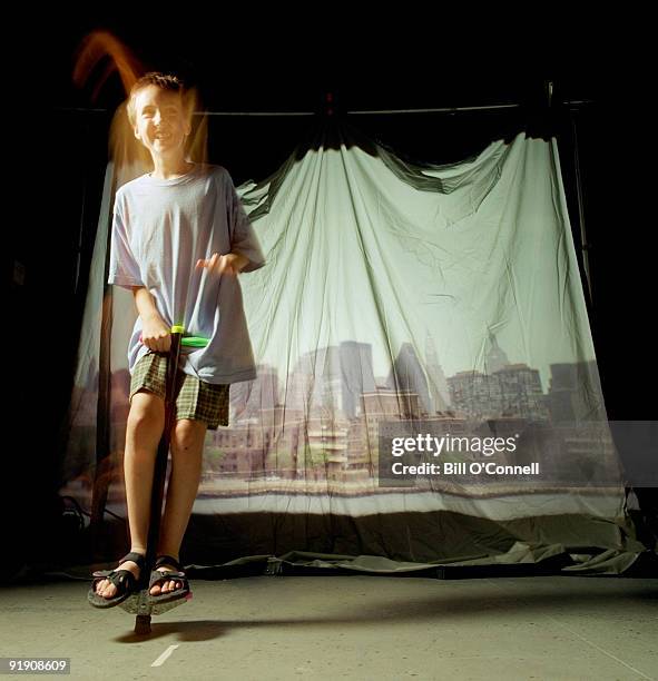 boy hopping in front of cityscape backdrop - pogo stock-fotos und bilder