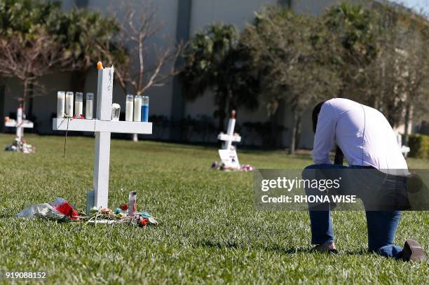 Mourner kneels in front of a memorial for the victims of the Marjory Stoneman Douglas High School shooting in a park in Parkland, Florida on February...