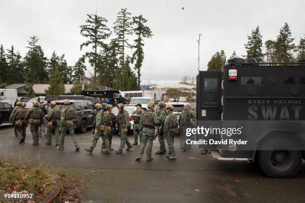 Members of a SWAT team walk through a campus parking lot after a threat of an active shooter shut down campus at Highline College on February 16,...