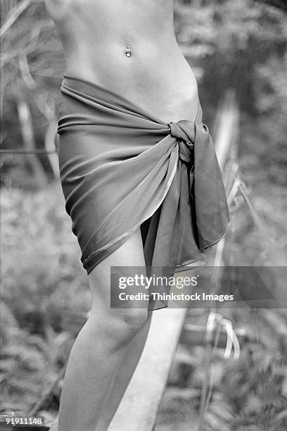 close-up of woman's hips in sarong, standing on plank and rope bridge in forest - belly ring stock pictures, royalty-free photos & images