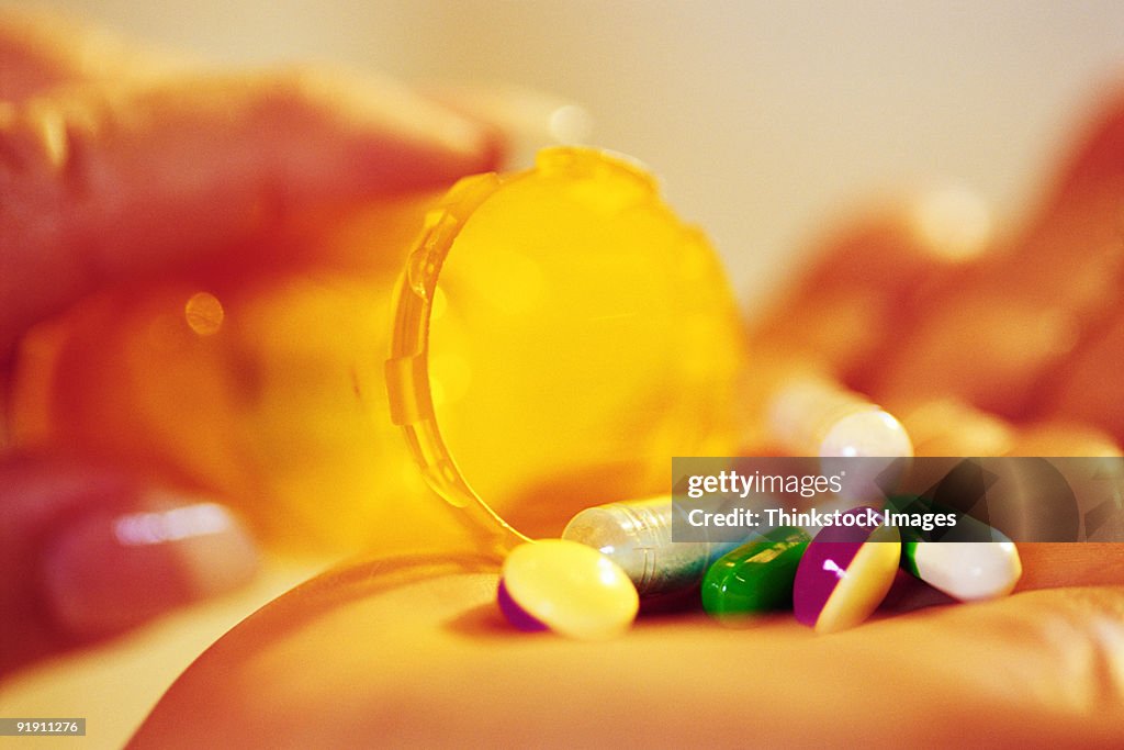 Close-up of pills being poured from bottle into hand