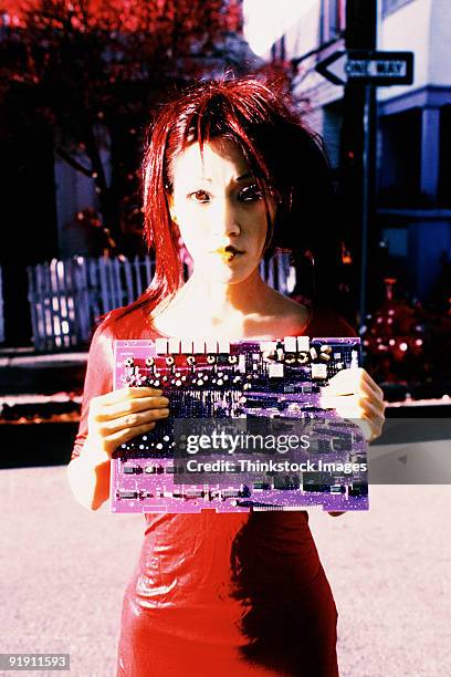 hip looking woman, standing in street holding circuit board up to her chest - printed circuit b stock pictures, royalty-free photos & images