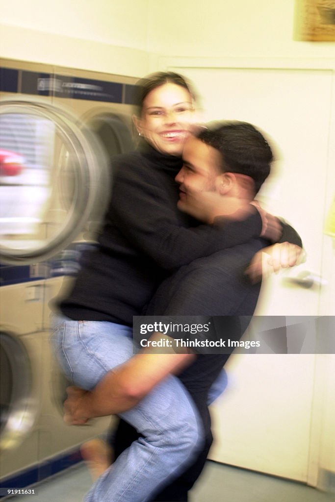 Young Hispanic male picking up a young Hispanic female in a laundromat