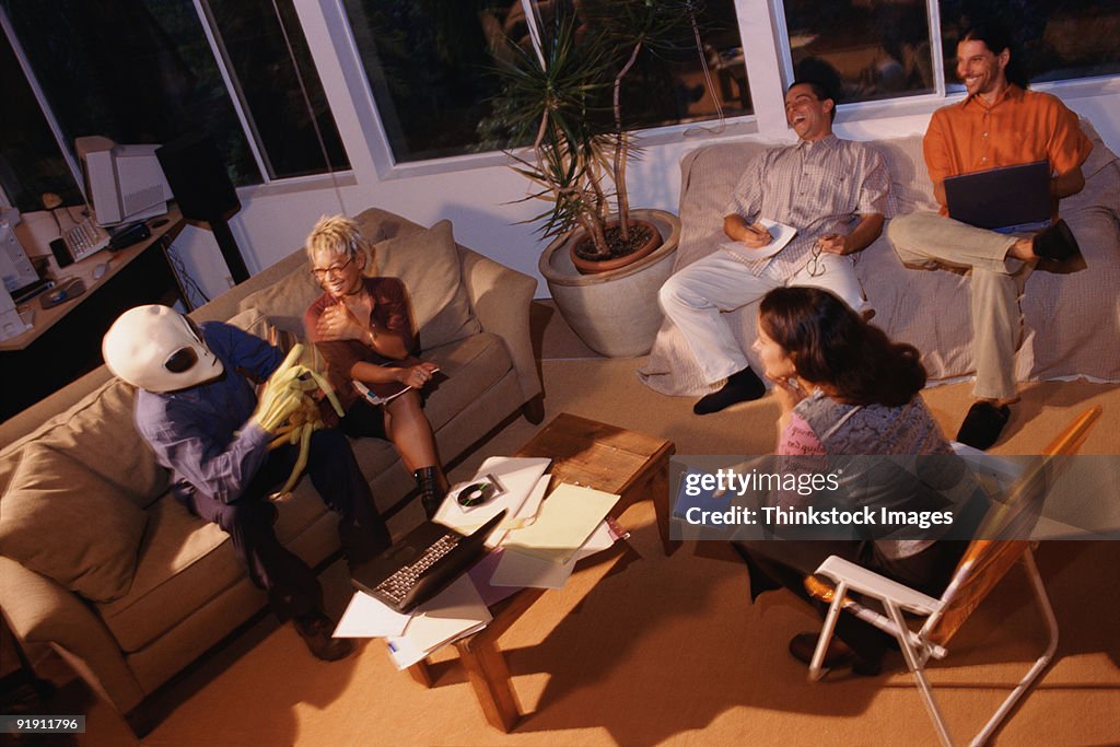 Alien talking to group of people, seated on couches and chairs