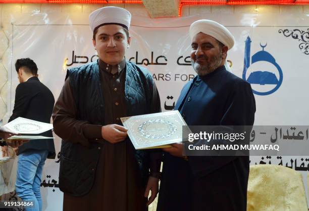 Sheikh Saleh al-Obeidi , head of the Muslim Scholars Forum of Mosul, hands out a certificate to a new graduate during a graduation ceremony in the...