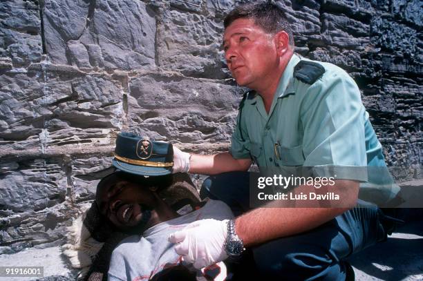 Immigration. A Civil Guard cover with its cap the head of an immigrant who lies in the ground, after to have arrived in patera.