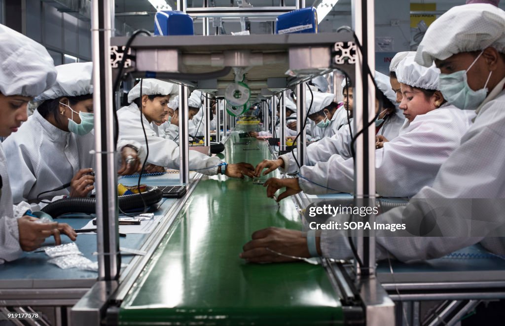 Workers assemble smartphones on the production line inside...