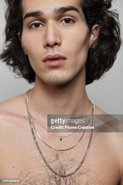 Portrait of young man with naked torso and necklaces