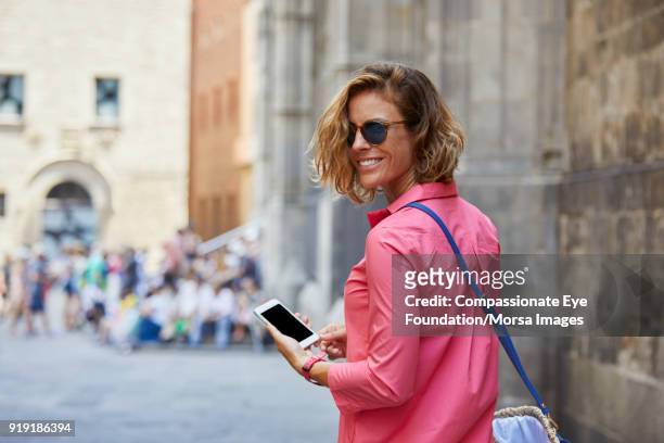 smiling woman texting on cell phone on street in barcelona - pink dress stock pictures, royalty-free photos & images