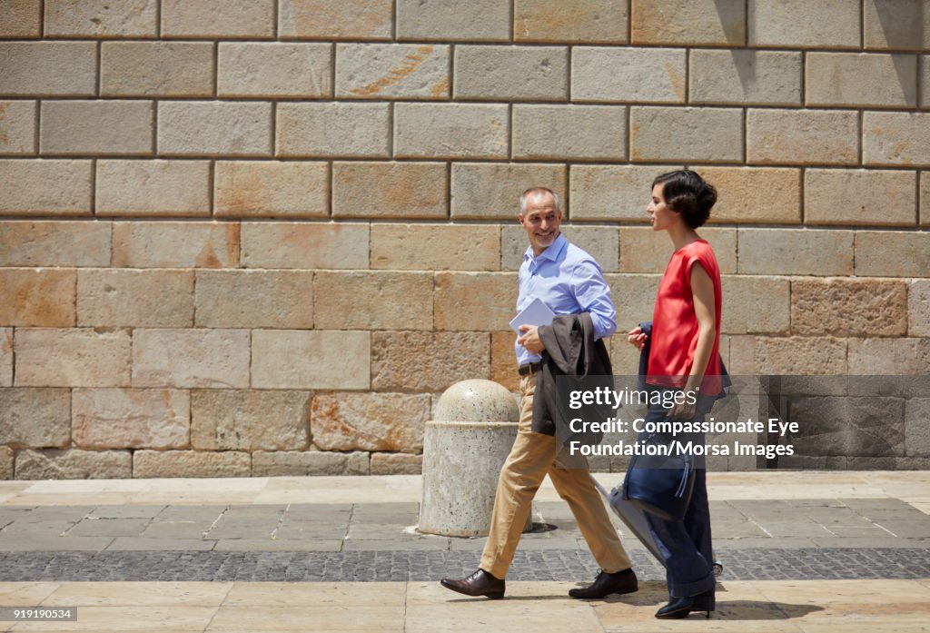 Businessman and businesswoman walking on street in Barcelona