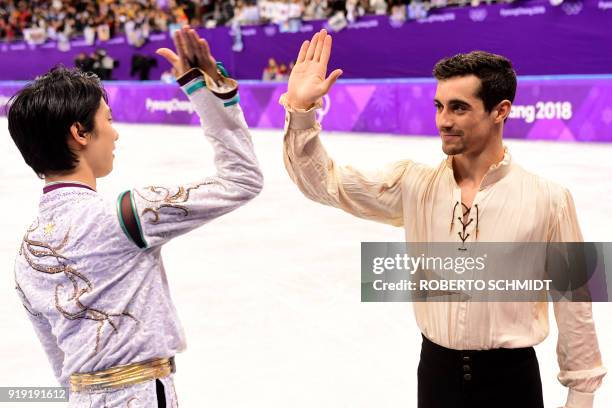 Winner Japan's Yuzuru Hanyu high fives third-placed Spain's Javier Fernandez during the venue ceremony after the men's single skating free skating of...