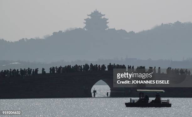 Tourists flock over a bridge on West Lake in Hangzhou, in eastern China's Zhejiang Province on February 17, 2018 as people spend the second day of...
